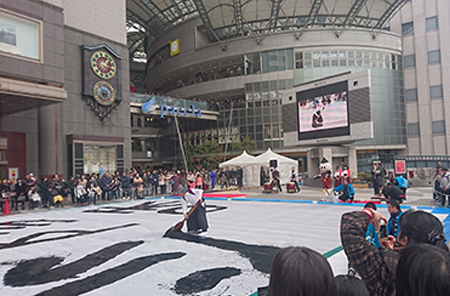 「新春ウルトラ書き初め会」で長さ1.8ｍの大筆を振るっている写真